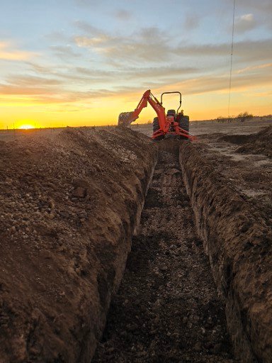 Construction crew performing a trench excavation in Plainview at dusk